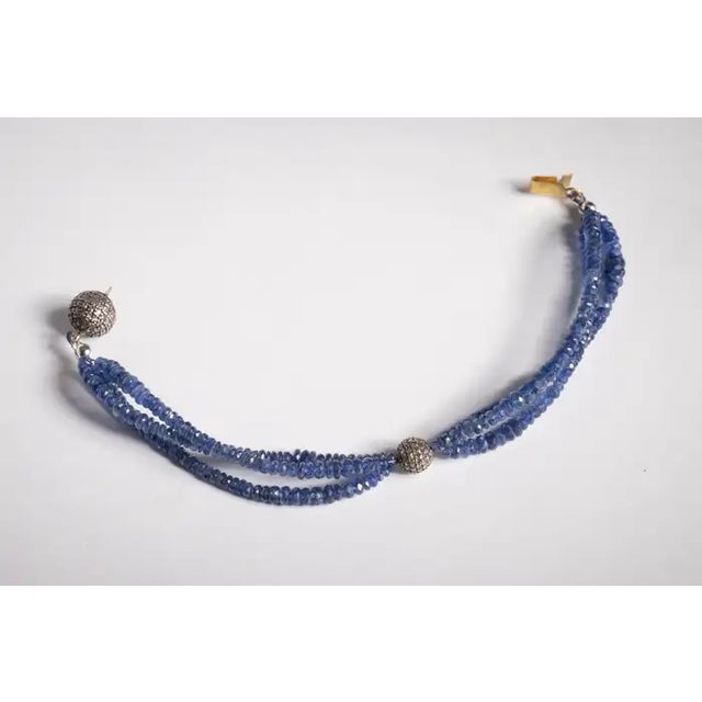 A triple line of lively, faceted blue sapphire gemstone beads with a round bead at the top featuring pave`set, round...