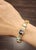 This ornate rainbow gemstone bracelet is a captivating expression of vintage sophistication and intricate design....