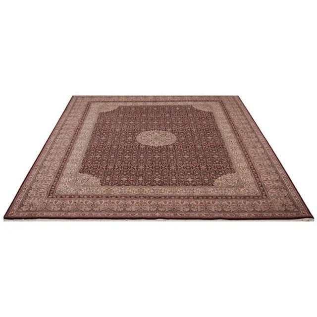 Handwoven wool rug featuring an Agra design with a burgundy background, light salmon-colored border, and ivory-colored...