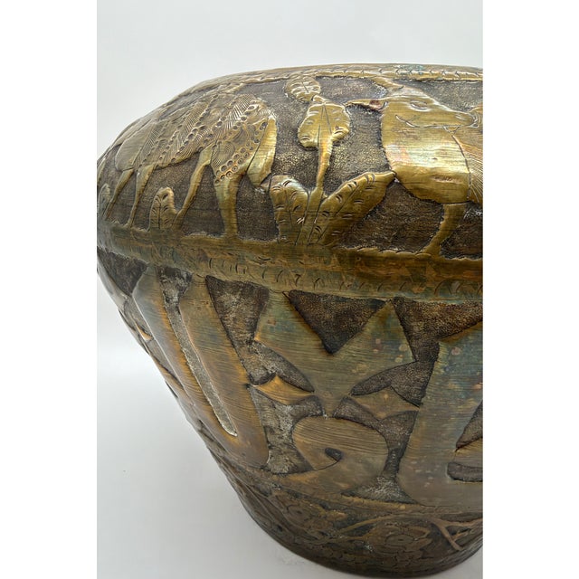 This large brass jardinière is decorated with horizontal bands of Arabic-style calligraphic ornament, goats and foliage....