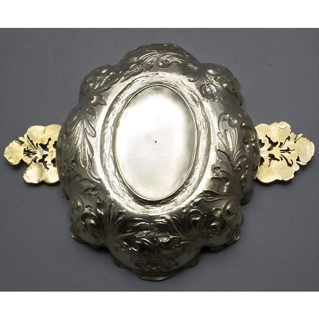 Silver, chased, engraved, and gilded. Harmonious oval shape with chased Dutch flowers, floral handles on the sides, and a...