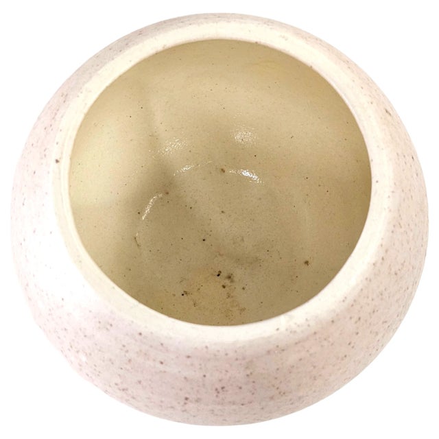 This mid-century studio art pottery bowl vase presents a compact, rounded form finished in a soft blush-pink glaze with...
