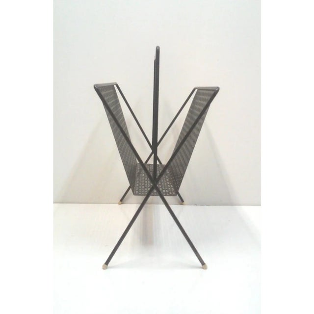 An Industrial perforated black sturdy magazine rack with square, geometric cut perforated design in the heavy duty steel...