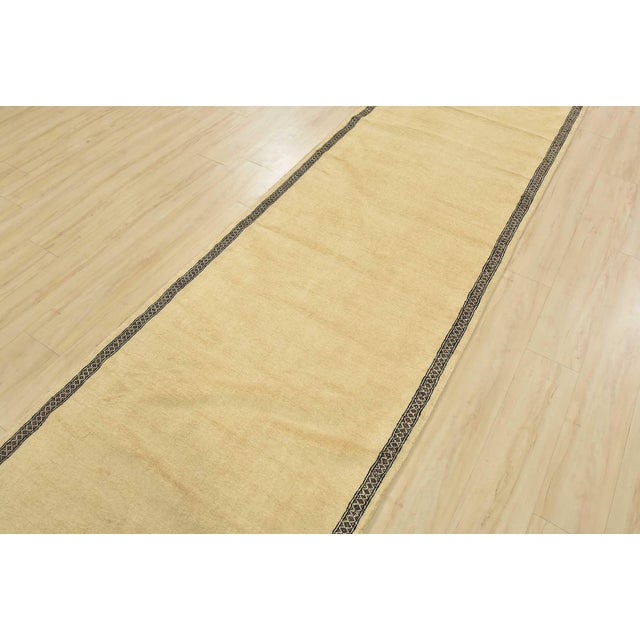 A tribal Bokhara runner hand-knotted with an all-wool pile on a cotton foundation. This finely woven oriental rug features...