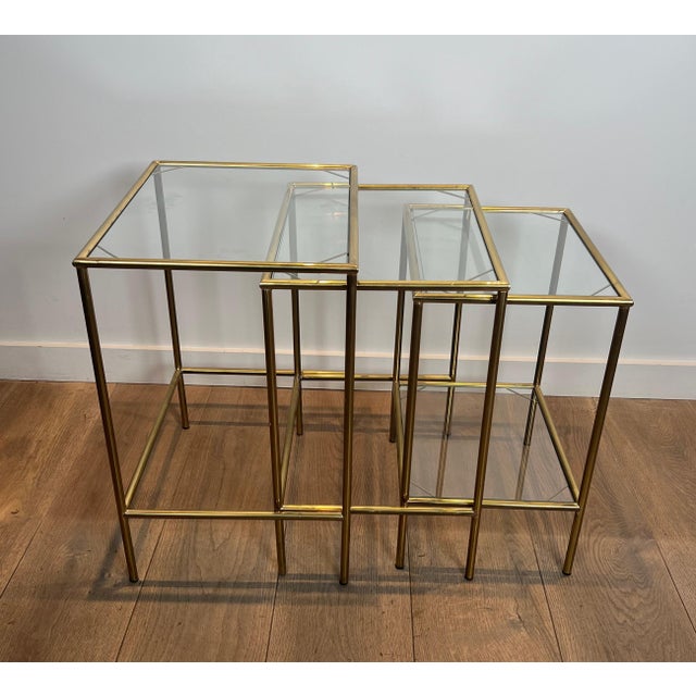 These neoclassical-style nesting tables are made of brass with glass shelves. This is a French piece. Circa 1940