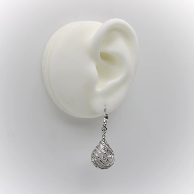 These drop-shaped rock crystal earrings are wrapped in masterfully hand engraved diamond encrusted cage settings. The 18k...