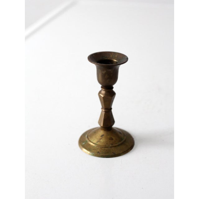 This vintage brass candlestick holder features a turned pedestal shape with a flared rim and traditional silhouette. The...