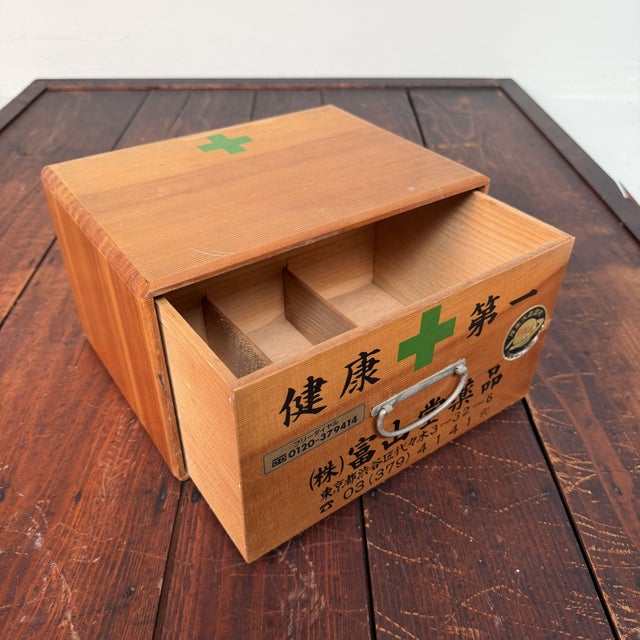 The front is decorated with Japanese text, a green medical cross and a metal handle. The large text at the top translates...