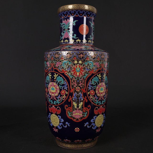 Elegant Chinese rouleau style porcelain vase with a rich deep navy blue base, decorated in vibrant famille rose enamel and...