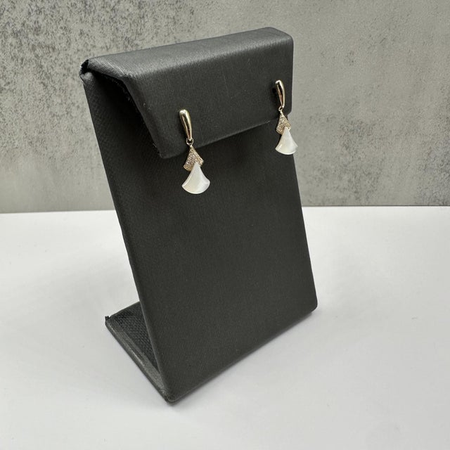 These elegant mother of pearl and diamond dangle earrings in 14kt yellow gold showcase luminous mother of pearl stones...