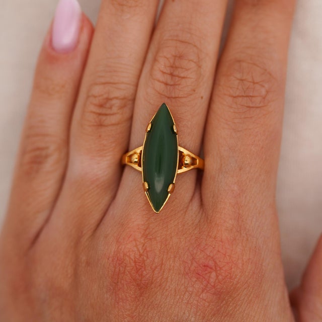 Vintage 18K yellow gold ring features an elongated 25 x 8mm dark green nephrite jade cabochon set vertically across an...