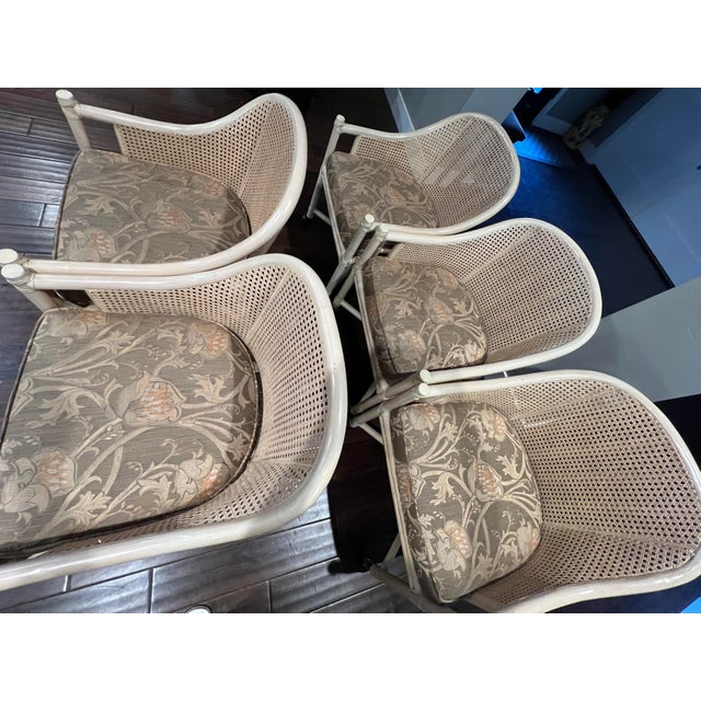 Each chair features a bleached/whitewashed rattan frame, honeycomb caning on the back and sides, and a loose seat cushion....