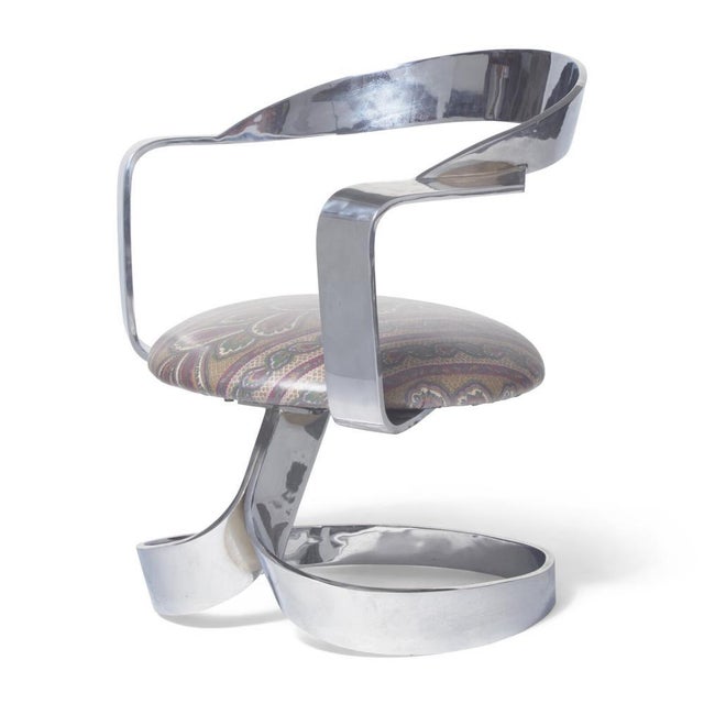 The "Cinta" swiveling armchair by Spanish designer Carlos Ojínaga Erill: a sculptural ribbon of stainless steel that wraps...