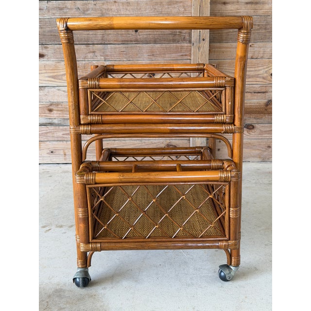 A charming vintage rattan bar cart featuring a two-tier design with woven rattan surfaces and built-in side bottle...