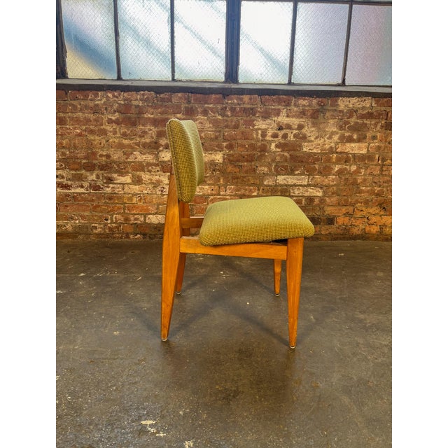 Classic dining chairs attributed to George Nelson, featuring a warm maple frame with splayed legs and green upholstery. A...