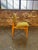 Classic dining chairs attributed to George Nelson, featuring a warm maple frame with splayed legs and green upholstery. A...