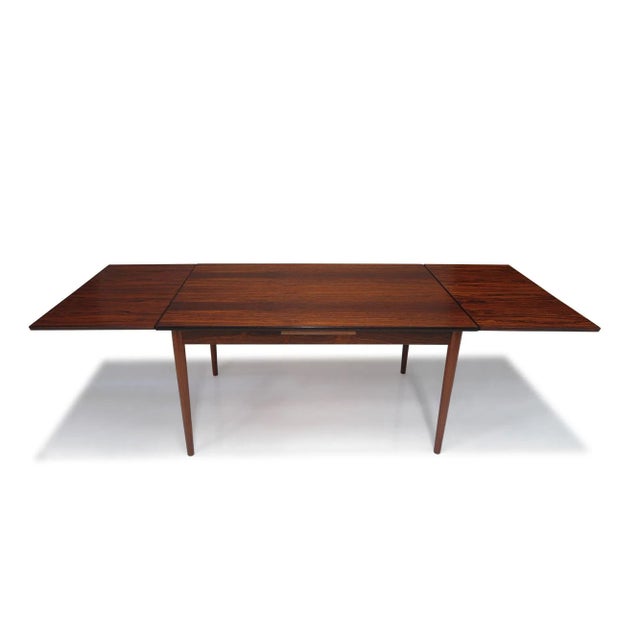Danish Brazilian rosewood dining table with draw-leaves raised by round tapered legs. (Unmarked) W 55,5’’ x D 35.25’’ x H...