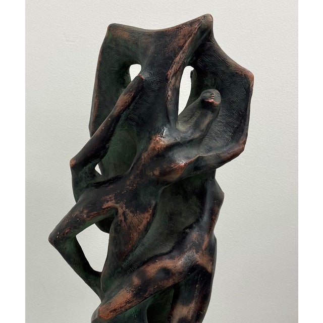 Hand carved ceramic sculpture depicting an abstract figure integrated within an organic pierced form. Finished in dark...