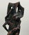 Hand carved ceramic sculpture depicting an abstract figure integrated within an organic pierced form. Finished in dark...