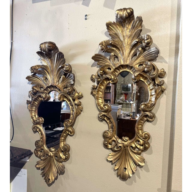 This impressive pair of antique Italian Louis XV style wall mirrors features elaborate Rococo carvings and a rich gold...