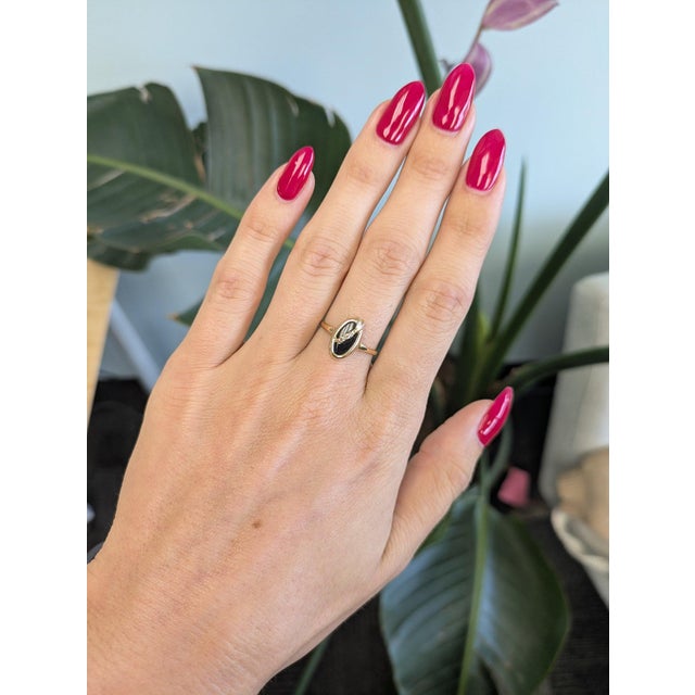A sleek black onyx anchors this solid 10K yellow gold estate ring, accented by a single earth-mined diamond. Onyx, a black...