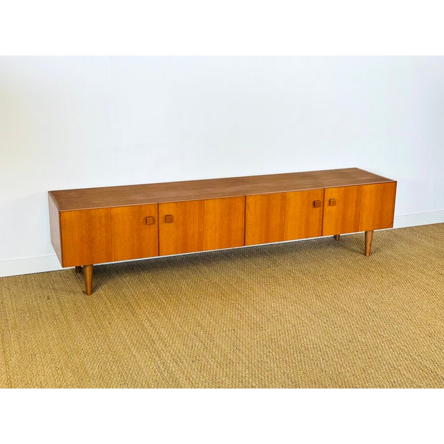 Elegant low scandinavian/vintage teak sideboard from the 1960s. with its minimalist lines, sculpted cubic handles, and...