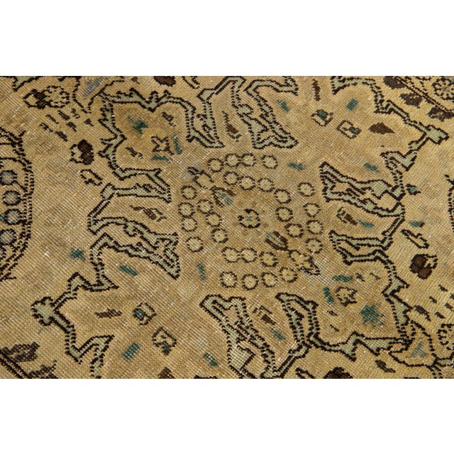 Beautiful antique Persian Tabriz hand-knotted wool rug with a tan color field. This piece has brown and green accents in...