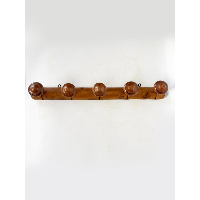 Antique wall-mounted coat rack in solid wood, featuring five rounded, button-shaped hooks. Its simple and robust design,...