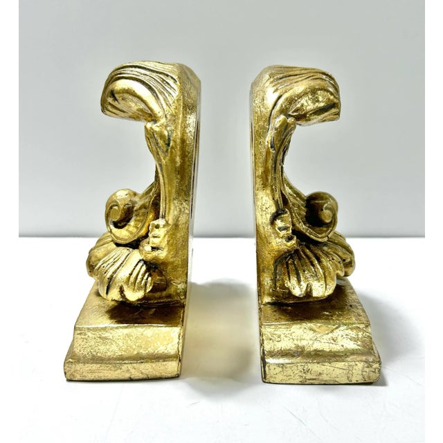 A decorative pair of vintage gold gilt shell bookends with Neoclassical and Rococo-style detailing. The sculptural shell...