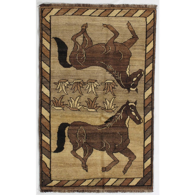 Persian Gabbeh hand-knotted wool rug featuring a warm camel-toned field with two stylized horse motifs, one depicted...
