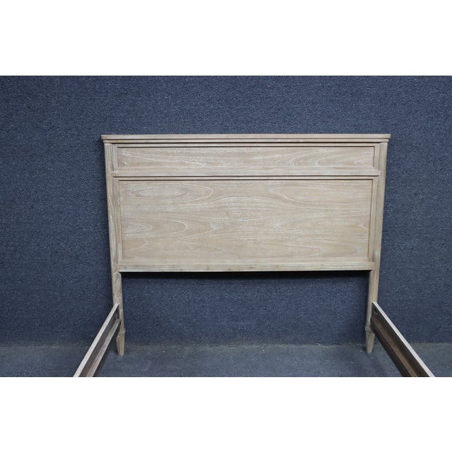 Whitewashed oak queen bed frame featuring clean paneled detailing, softly rounded edges, and tapered legs. Finished in a...