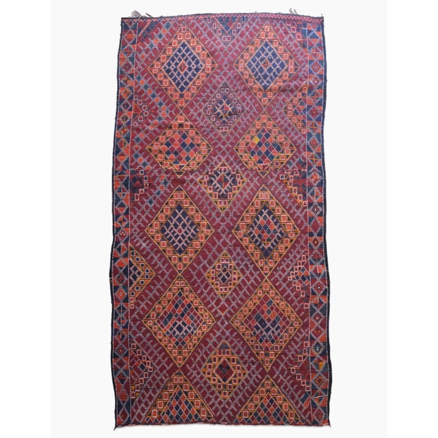 This handwoven wool rug from 1970s Morocco embodies a rich heritage through its deep reds and indigos. Its diamond...