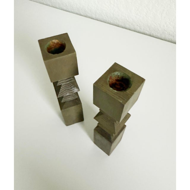 A pair of 1950s oak wood candlesticks with a muted olive green painted finish. The stick center features a zigzag cut,...