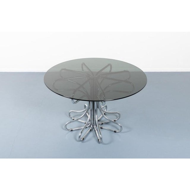 Vintage Italian design round dining table from from 1970s. Sculptural chromed tubular steel base with loose smoked glass...