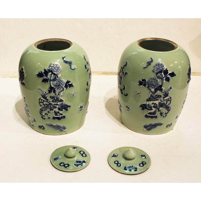 Circa 1880 pair of covered porcelain jars, Chinese. Celadon with blue & white pate-sur-pate motifs of a scholar's table,...