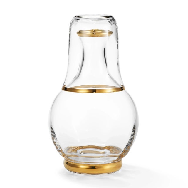 This beautifully crafted carafe and tumbler set, enhanced with hand-painted gold, is an elegant addition to a bedside...