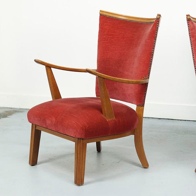 A pair of vintage armchairs featuring oak frames of exceptional quality with beautifully curved backs and armrests, giving...