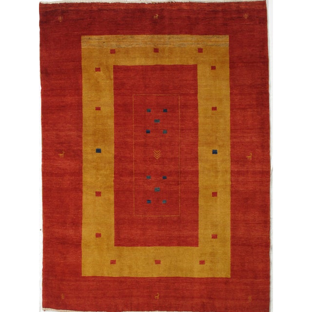Vintage Hand-knotted Persian Lori Gabbeh rug featuring a bold geometric composition with a deep red field framed by a wide...