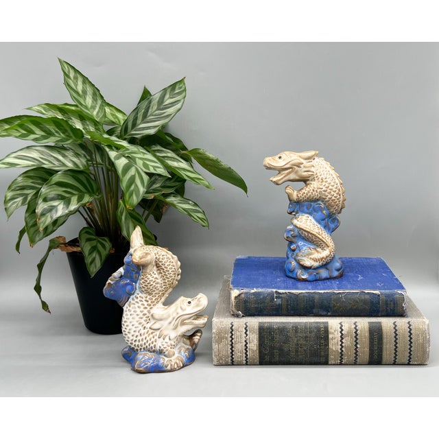 Striking pair of mid to late 20th century ceramic dragons perched atop vivid cobalt blue waves. Each dragon features...