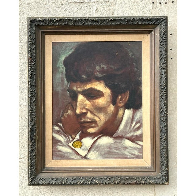 This framed portrait captures a moment of quiet poise and introspection—a man leans slightly forward, arms crossed on a...