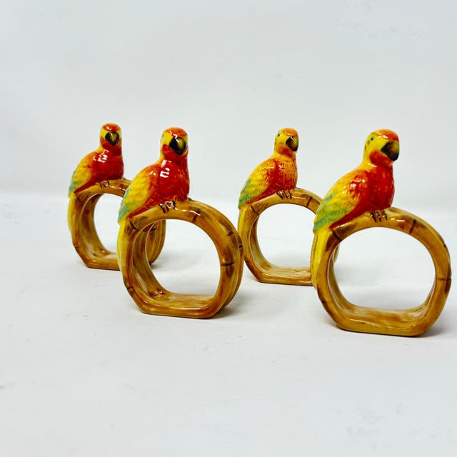 A set of eight faux bamboo and ceramic parrot napkin holders, hand painted in tropical colors. Bamboo holders are included.