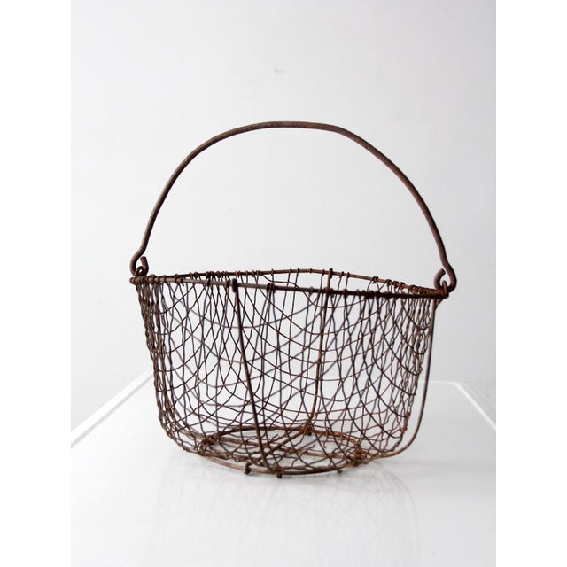 Antique handmade wire gathering basket dating from the 1920s–1940s, featuring a classic primitive farmhouse form and...