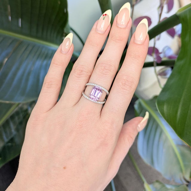 A luminous 6.2ct natural kunzite takes center stage, glowing in soft blush tones and framed by shimmering earth-mined...