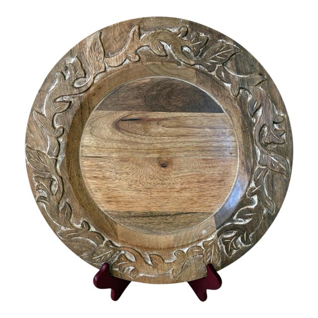 A coordinated set of four Pier 1 Imports wooden charger plates featuring carved leaf-and-vine borders accented with a soft...