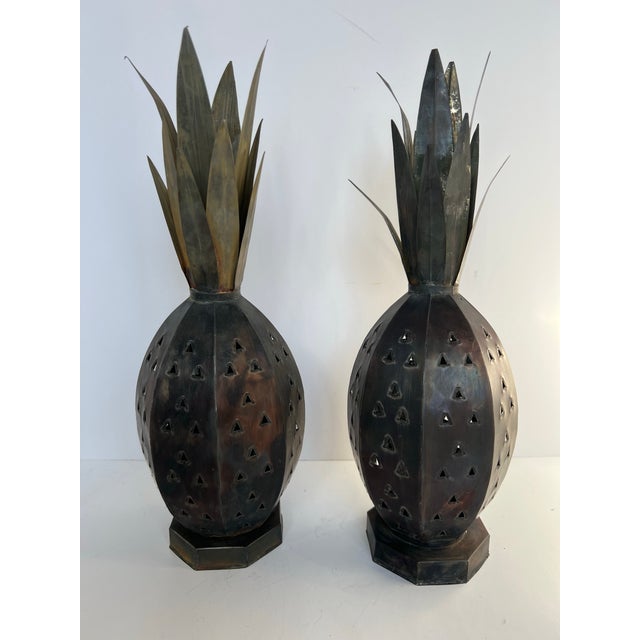 A sculptural pair of handcrafted Mexican punched tin lanterns in the form of pineapples, a traditional symbol of...