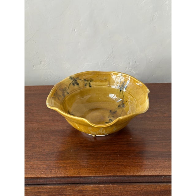 Signed studio pottery wavy rim bowl with rich glaze and floral embellished interior. Appears to be a very light colored...