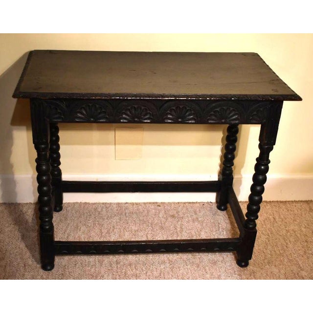 A baroque form English 17th century side table is of dark oak or elm. The overhang is detailed with leafage carving. The...
