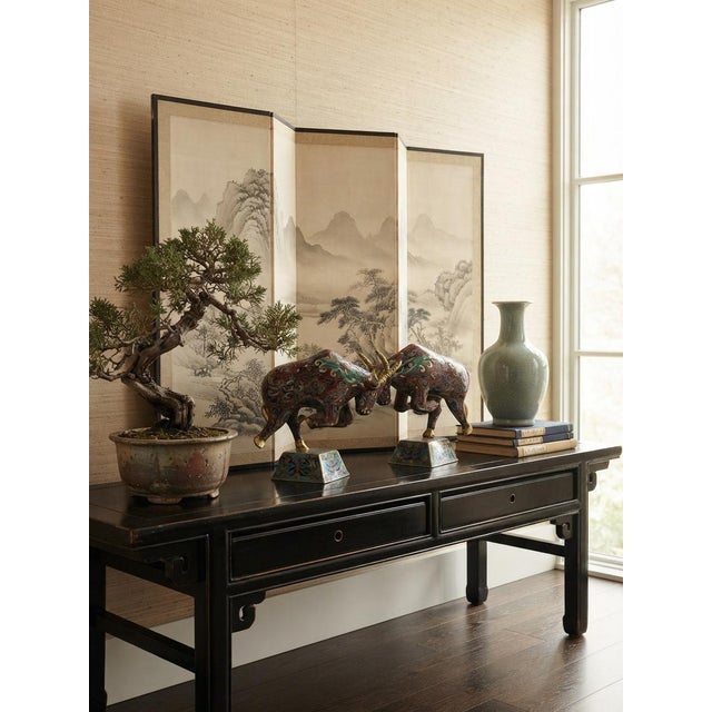 This pair of vintage Chinese cloisonné enamel figures depicts dynamic bulls in mid-charge, masterfully rendered with rich...