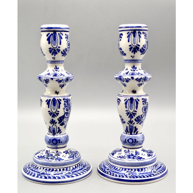 A lovely pair of Mid Century Dutch Delft candlesticks. They are hand painted in the traditional colors of blue and white...