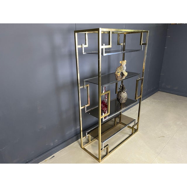 Hollywood regency wall unit. It consists of symmetrical brass and chrome shelves with smoked glass tops. Great to display...
